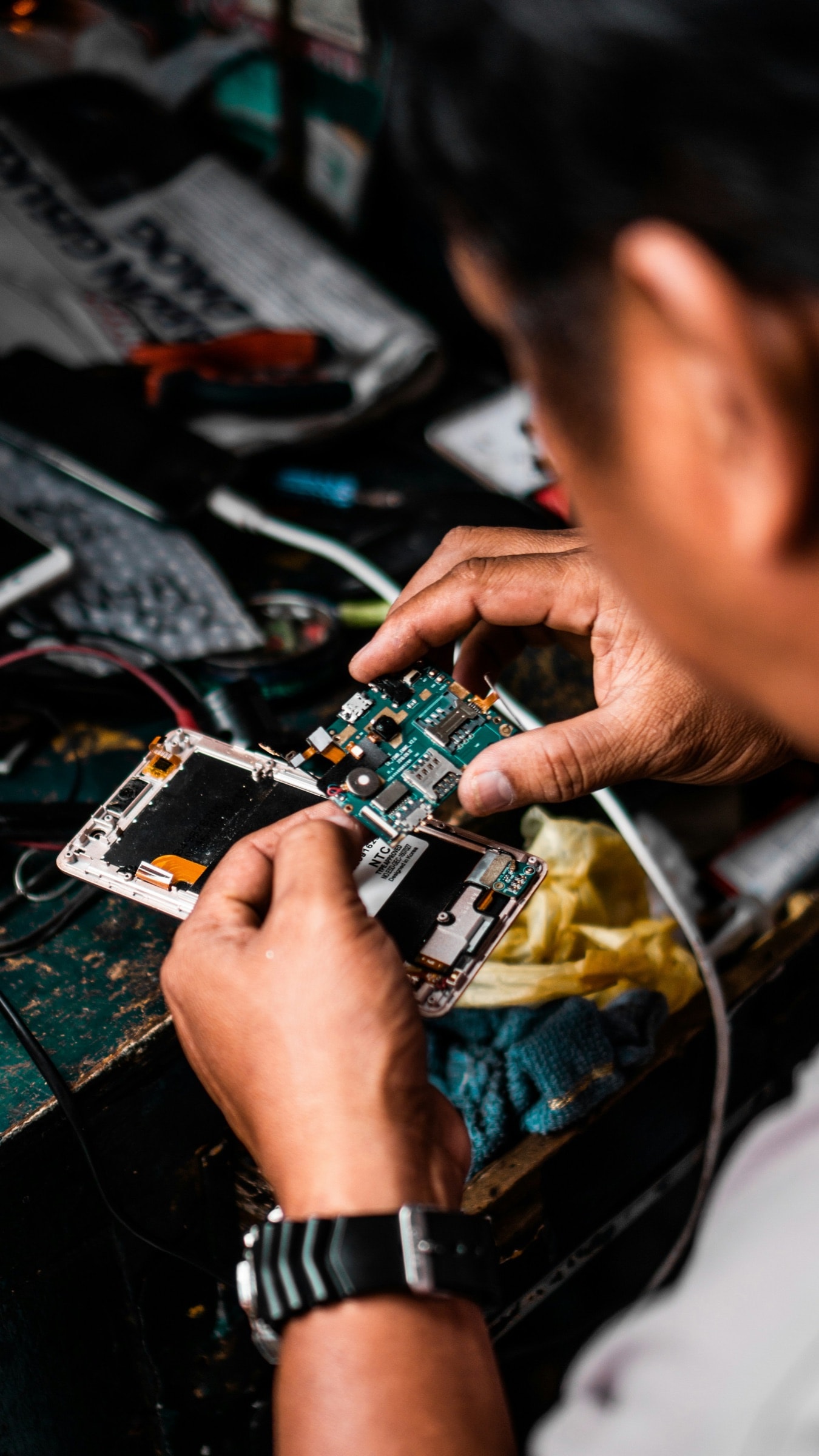 A technician repairing a phone logic board